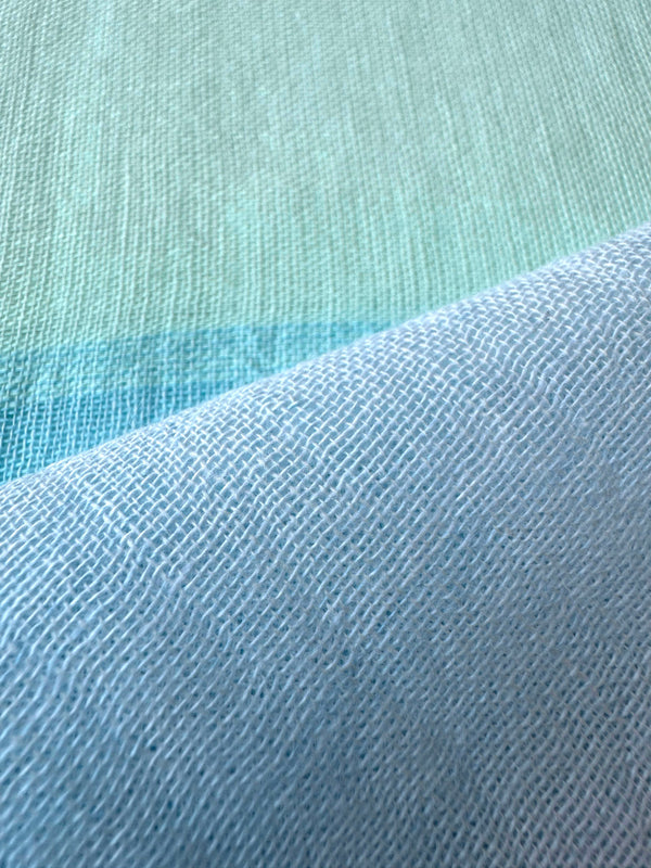 Close up on lemlem handwoven Nefas Mint fabric featuring pale blue, aqua blue and green mint color