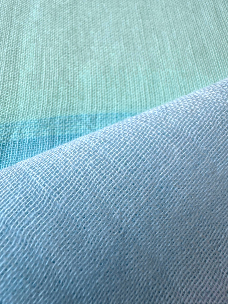 Close up on lemlem handwoven Nefas Mint fabric featuring pale blue, aqua blue and green mint color