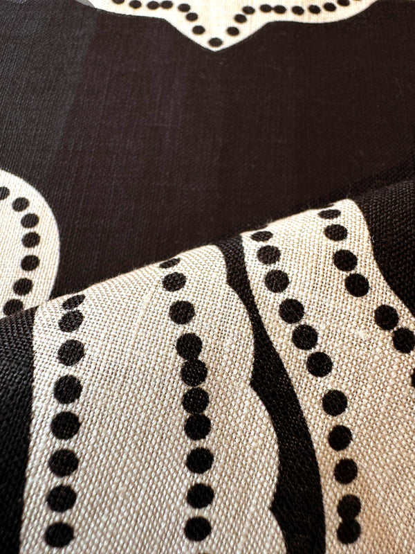 Close up on lemlem niku black fabric featuring ancient inspired pattern in cream color on black background and a matching tank top