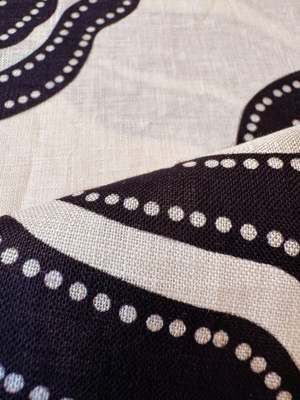 Close up on  lemlem Niku Cream linin fabric featuring ancient inspired pattern in black color on cream background and beige denim shorts