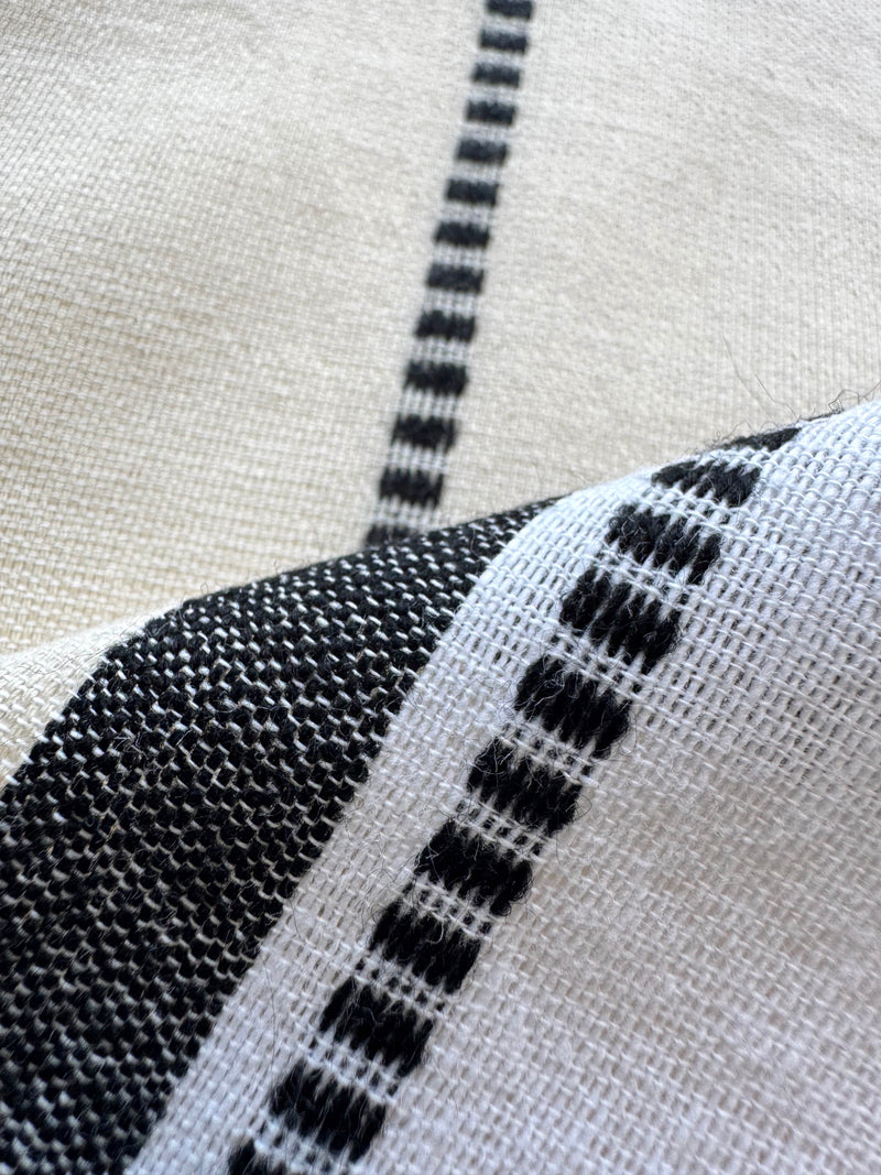 Close up on lemlem handwoven fabric featuring  refined palette of crisp white, soft cream, and deep black