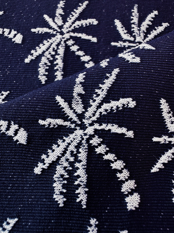 Close up on lemlem Zafi Navy swim fabric featuring ivory palm tree motifs set against a rich navy background.