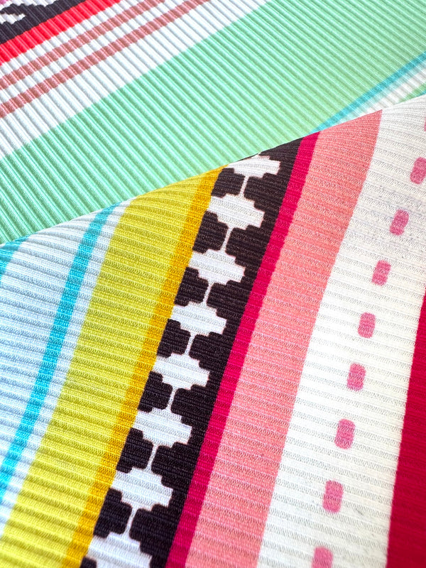Close up on lemlem swim fabric featuring intricate stripes and a tibeb pattern in vivid combinations of green, aqua, turquoise, pink, and soft peach-tangerine tones.