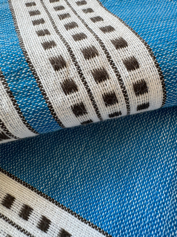 Close up on lemlem Amira Baltic Fabric featuring classic Amira pattern with small geometric bands that float on a rich teal blue ground