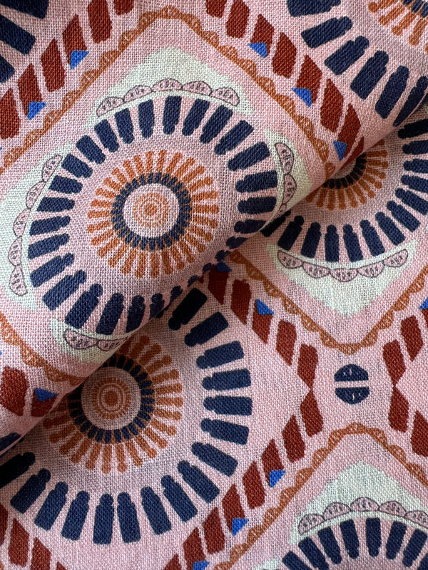 Close up on lemlem Fozia Rose linen fabric featuring a Yani Tibeb-inspired pattern in peach, rust, and orchid hues, accented with a bold citrus yellow pop.