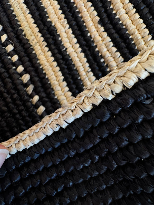 Close-up of a black and beige hand-crocheted raffia bag.