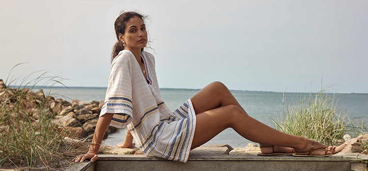 Woman Standing on the beach wearing lemlem linen pants featuring tibeb inspired pattern in white on navy background and matching swimsuit