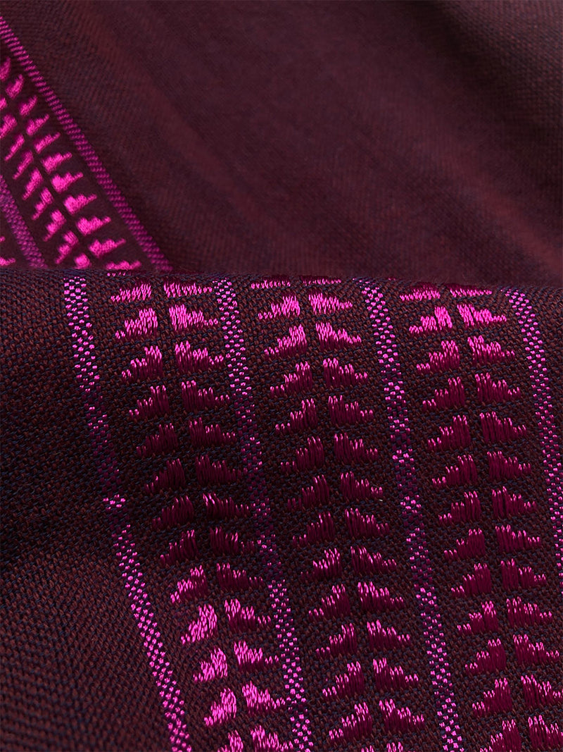 Close up on the fabric of the Edna V Neck Dress featuring rich, luxurious burgundy tones with hints of magenta. A matte and shining finish accentuates the depth of color and delicate woven textures.