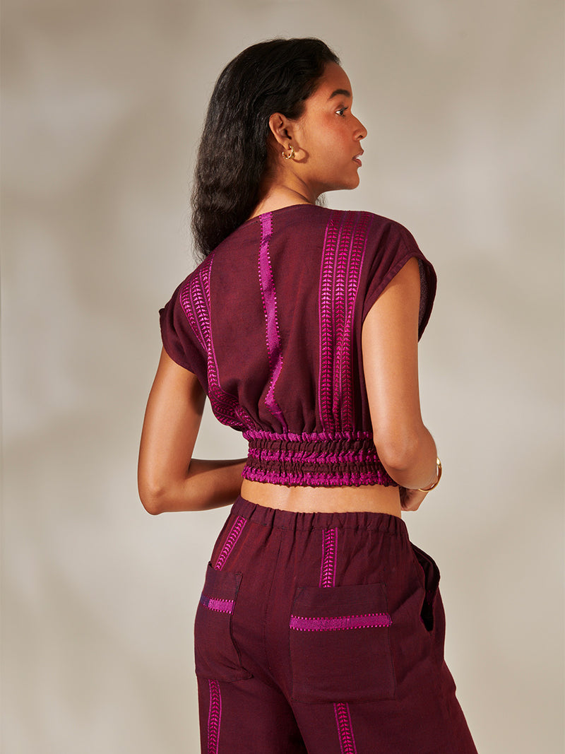 Back View of Woman Standing Wearing Alia Plunge Top featuring rich, luxurious burgundy tones with hints of magenta and Desta Pants