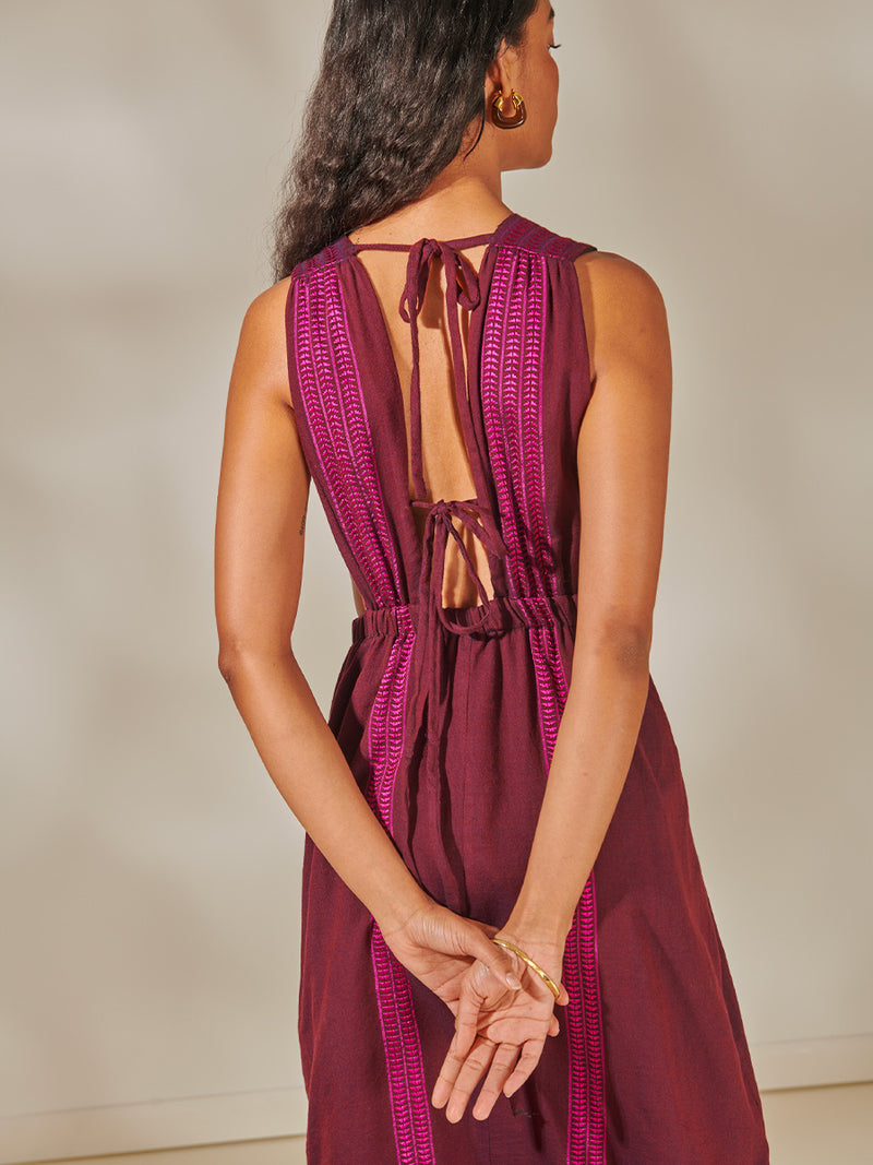 Back of a Woman Standing Wearing Lelisa V Neck Dress featuring rich, luxurious burgundy tones with hints of magenta.
