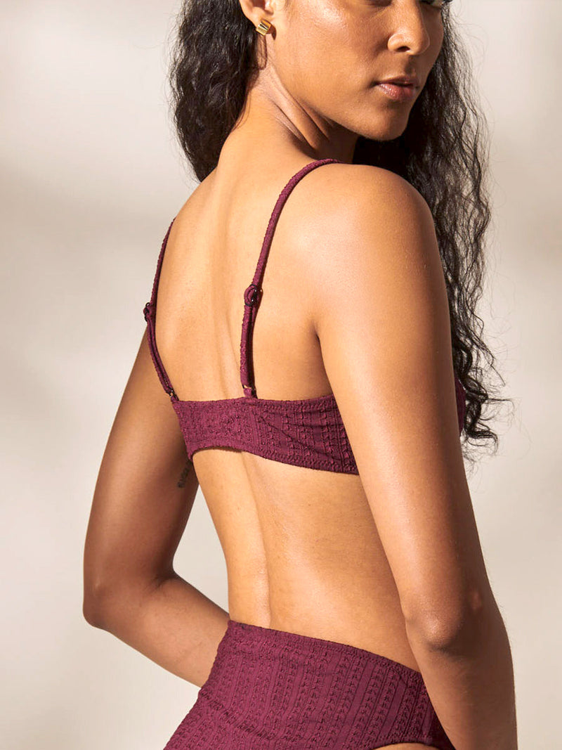 Back of a Woman Standing Wearing Sara Tie Front Top and High Waist Bikini Bottom featuring a downsampled Jordanos Pattern in a luxurious burgundy hue