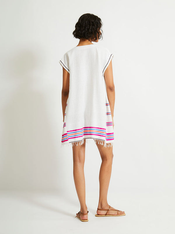 Back View - Woman Standing Wearing lemlem Elina Caftan featuring stripe pattern of bright magenta, blue, and orange on s crispy white background. 
