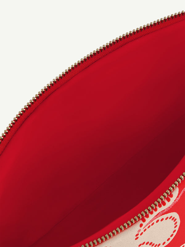 Product close up on lemlem pouch featuring ancient inspired pattern in white color on red background