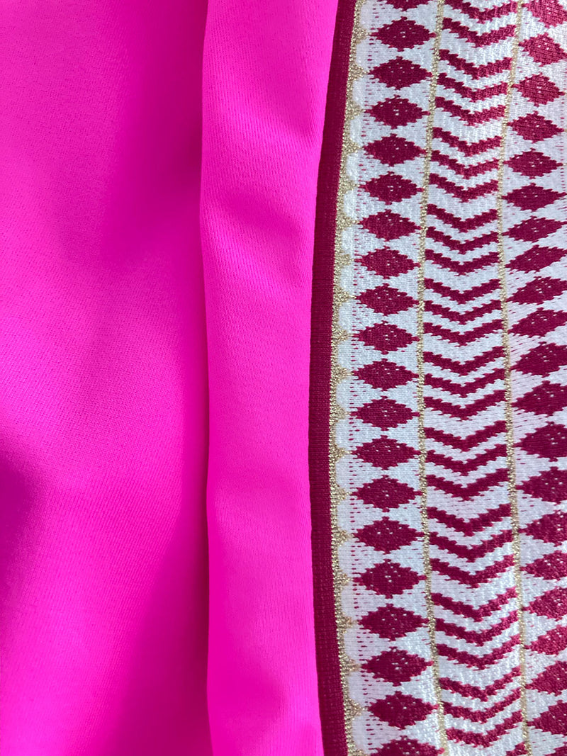 Close up on the fabric of the Lena Bralette Top in bright neon pink with a bordeaux diamond trim.