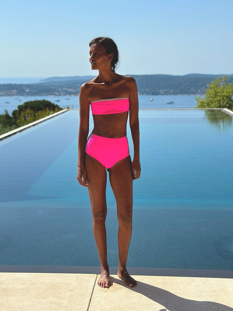 Liya Kebede stands by the infinity blue pool, wearing Lena High Waist Bottom and Lena Bandeau Top.