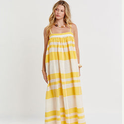 Woman standing wearing lemlem handwoven long EDA Dress featuring striped pattern in yellow on beige background