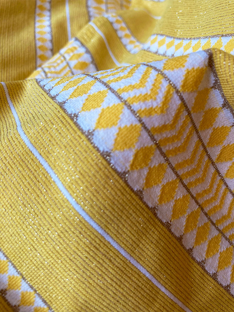 Close up on a yellow travel pouch featuring white vertical graphic stripes and a black zip closure at the top.