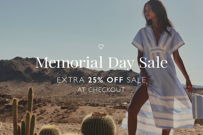 Woman in a lemlem handwoven blue dress standing in a desert with Memorial Day Sale text overlay.