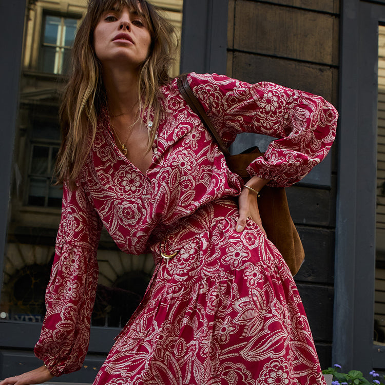 Woman wearing a red and white patterned dress standing against a dark background
