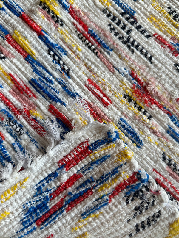Close-up of a textured fabric of lemlem upcycled handwoven MESFIN Rug with multicolored patterns