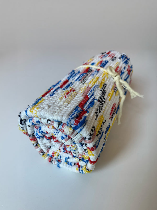 Rolled  lemlem upcycled handwoven MESFIN Rug with multicolored patterns