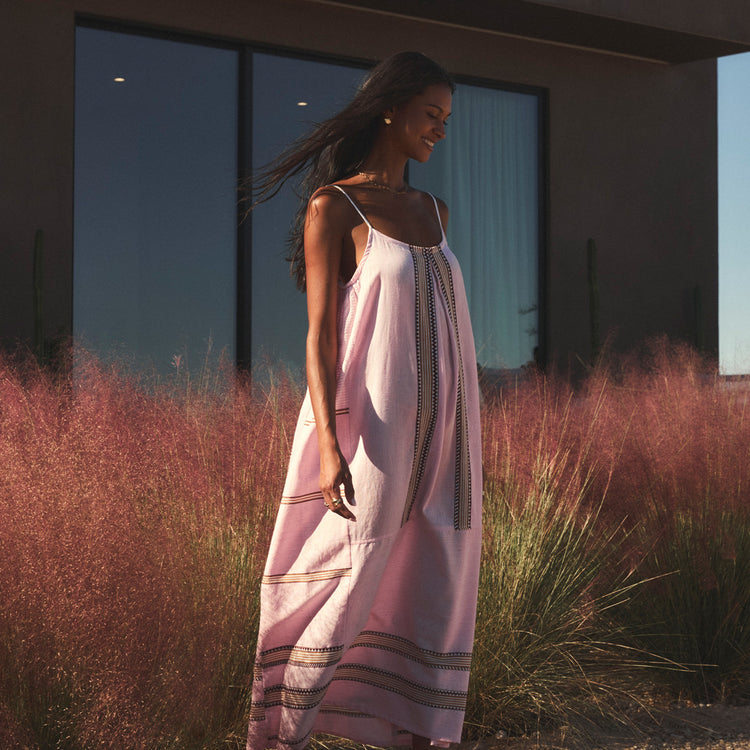 Woman in a pink dress standing in front of a modern building with purple grass.
