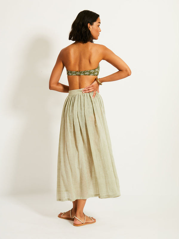 Back of a Woman Standing Wearing lemlem FREYE Skirt featuring airy gauze fabric in a delicate earthy sage color