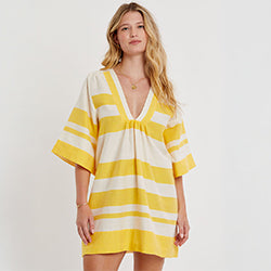 Woman Standing wearing lemlem BELKIS Caftan featuring yellow striped pattern in yellow color on beige background