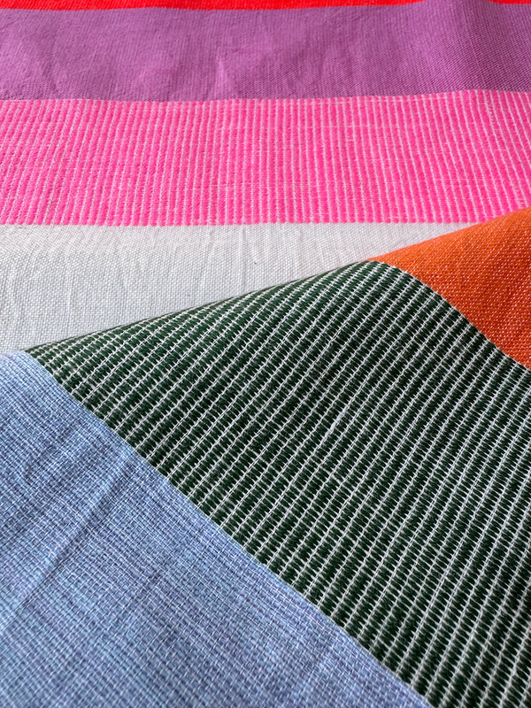 Close-up of lemlem handwoven fabric with pink, green, and blue patterns