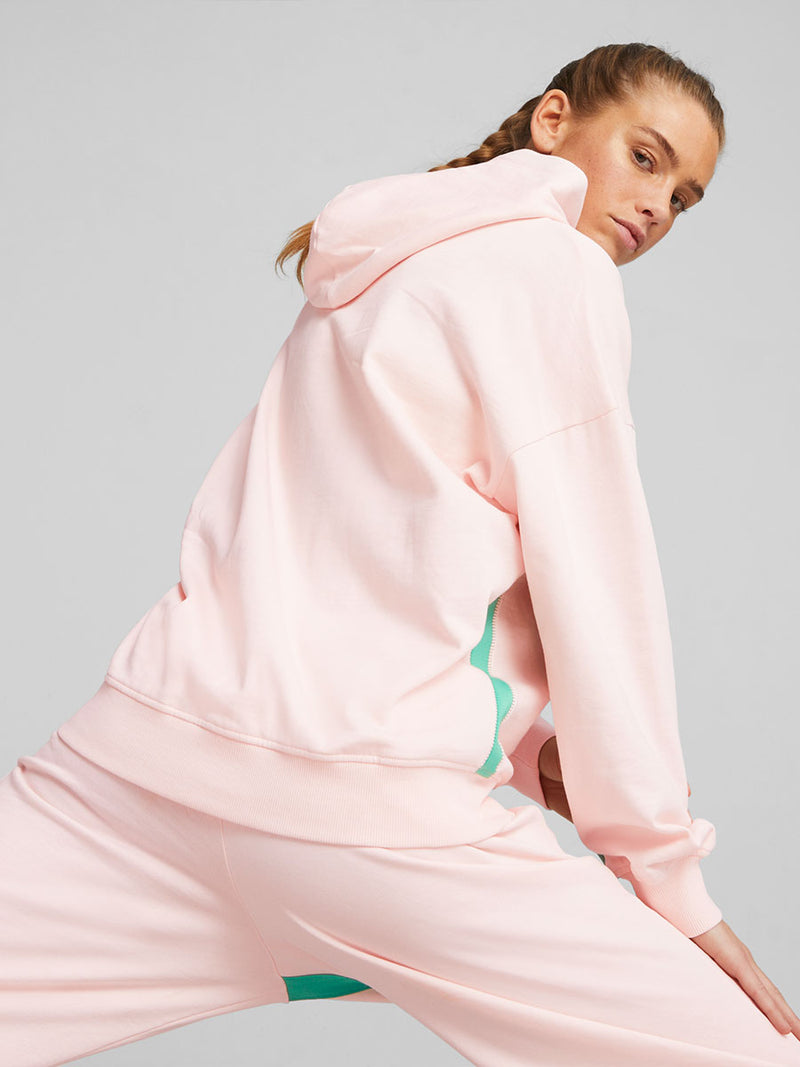 Woman exercising wearing Puma x lemlem fleece oversized hoodie and joggers in Ghost Pepper Color featuring color pop side stripes in pink and green colors and handsketched puma cat logo