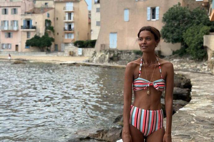 Liya Kebede wearing a colorful striped AVA Bandeau top featuring multicolor striped pattern on blue background and a matching bottom
