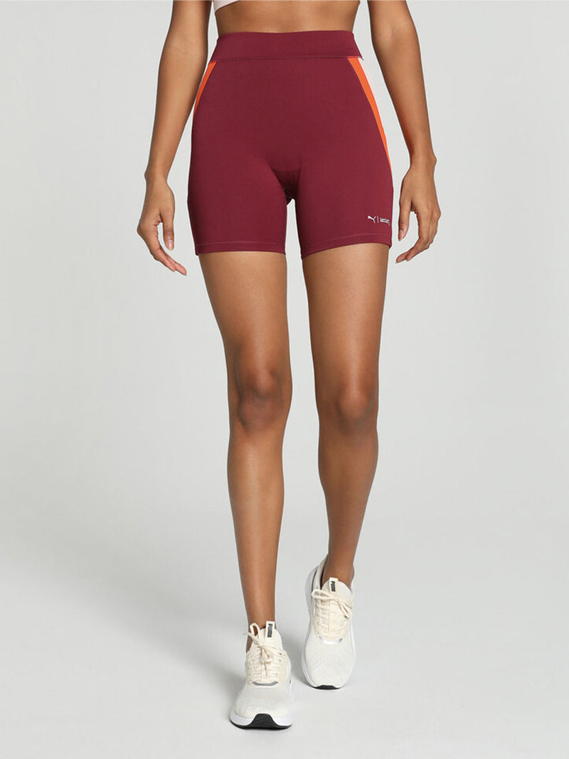 Legs of a woman standing wearing Puma x lemlem Biker Shorts Featuring Team Regal Red Color and color block details on hips in Warm White and Cayenne Pepper Colors