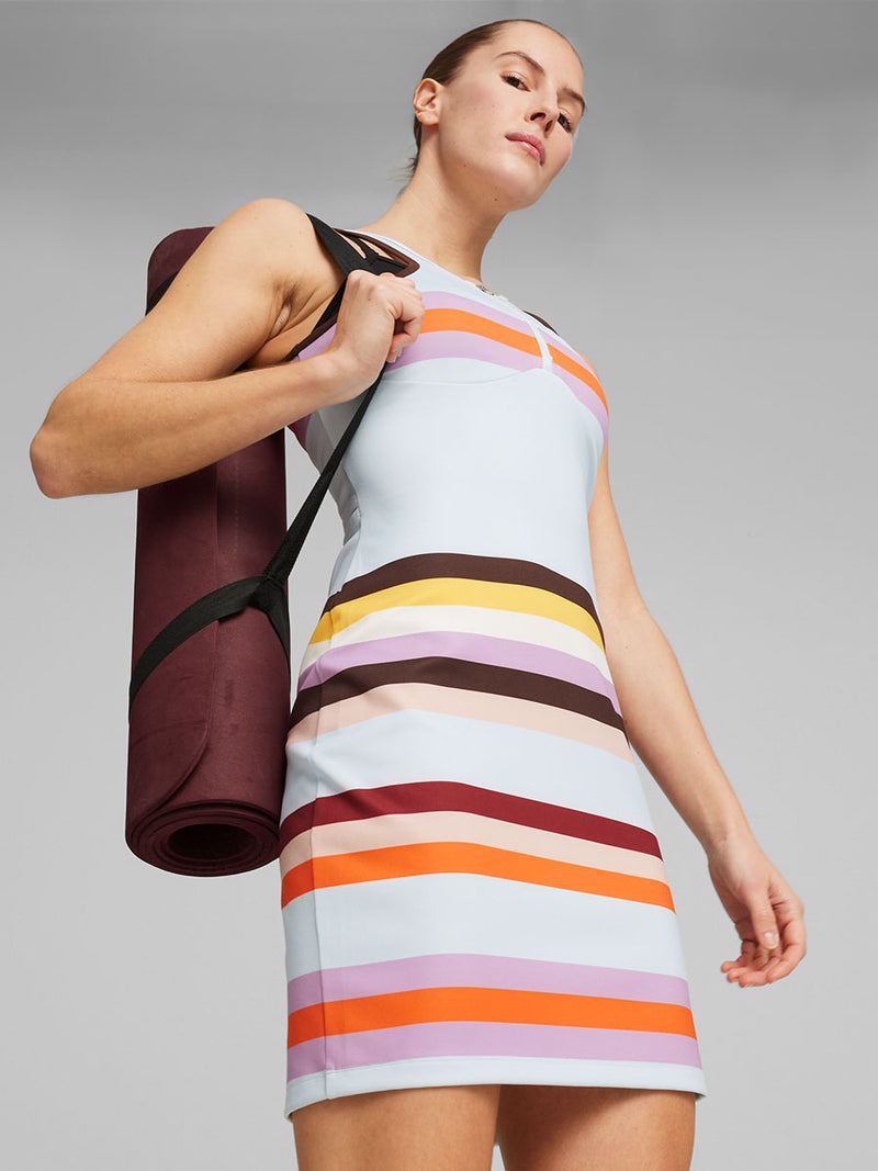 Woman Standing wearing puma x lemlem Dress Featuring Color Block Pattern in Icy blue, orange, violet, dark chocolate, yellow, white and rose colors