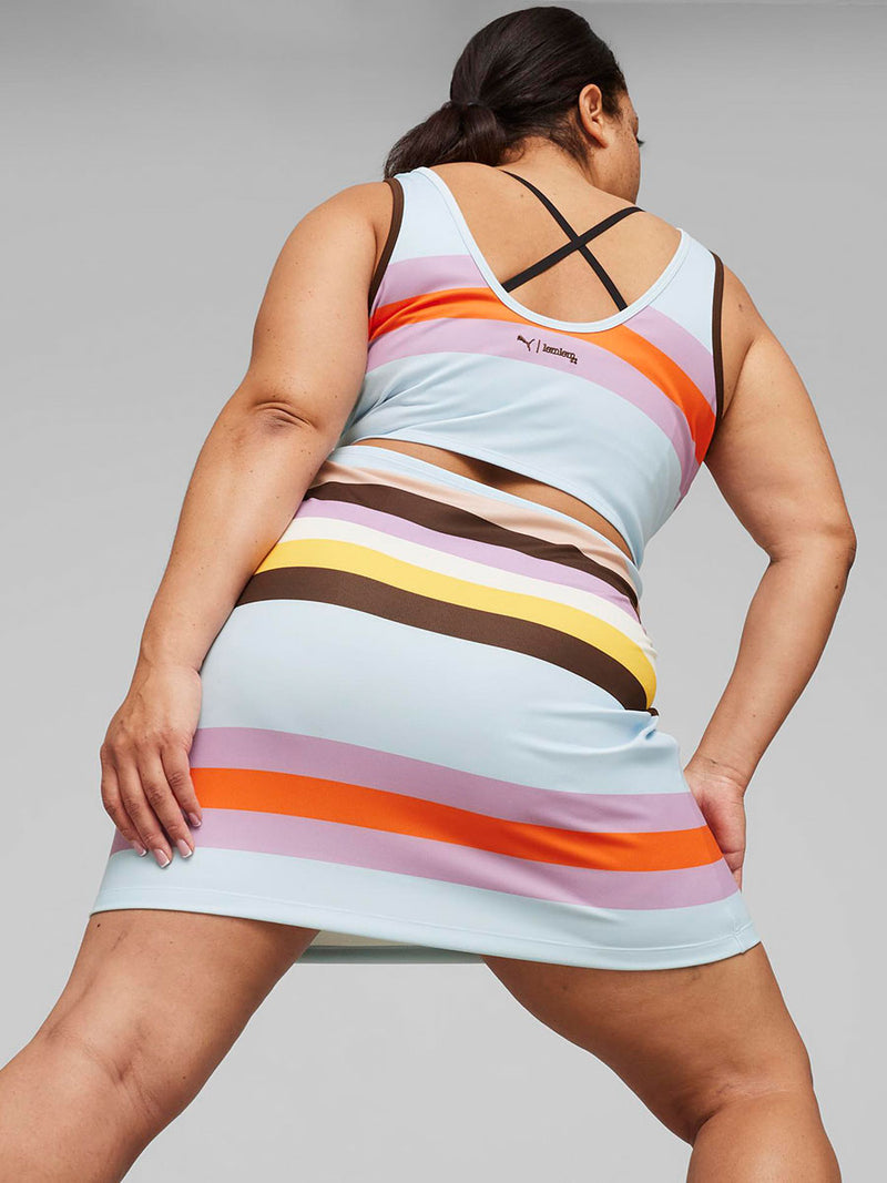 Back  View of a Woman Standing wearing puma x lemlem Dress Featuring Color Block Pattern in Icy blue, orange, violet, dark chocolate, yellow, white and rose colors