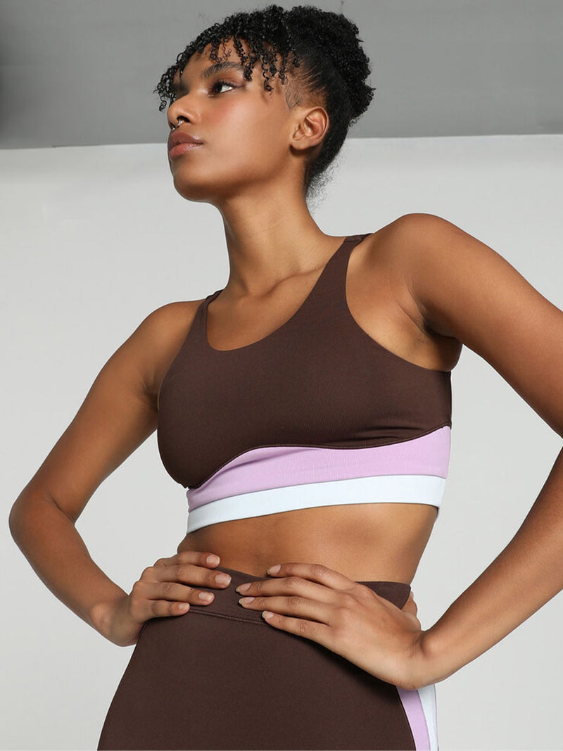 Woman Standing Wearing Puma x lemlem Crop Tank Featuring Dark Chocolate Color and Color Block Details on the Under Band in Violet and White colors and matching biker shorts