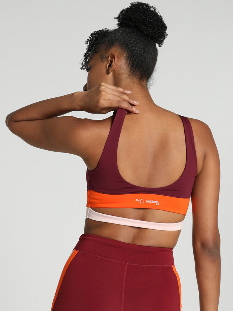 Back View of a Woman Standing Wearing Puma x lemlem Crop Tank Featuring Team Regal Red Color and Color Block Details on the Under Band in Orange and White colors and biker shorts