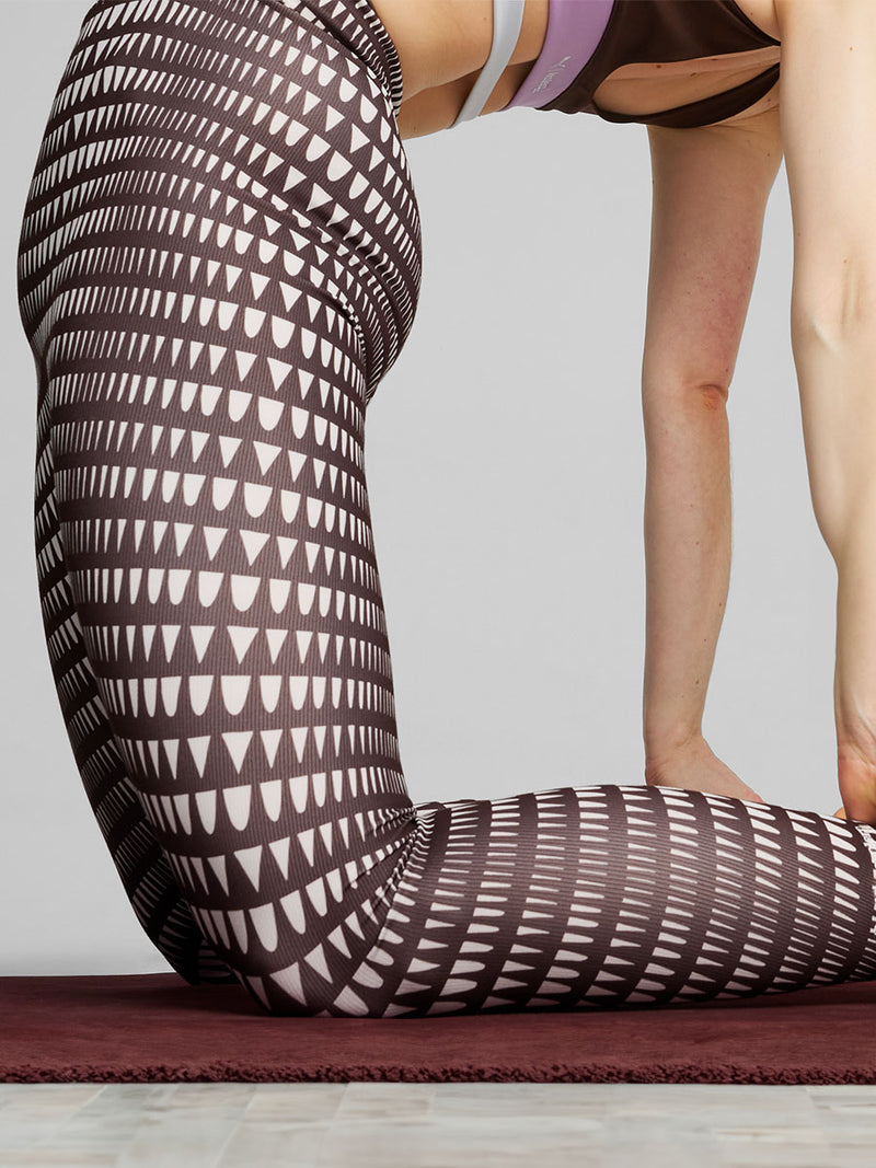 Woman Exercising Wearing Puma x lemlem Leggings in Dark Chocolate Color featuring lemlem triangle pattern in white color