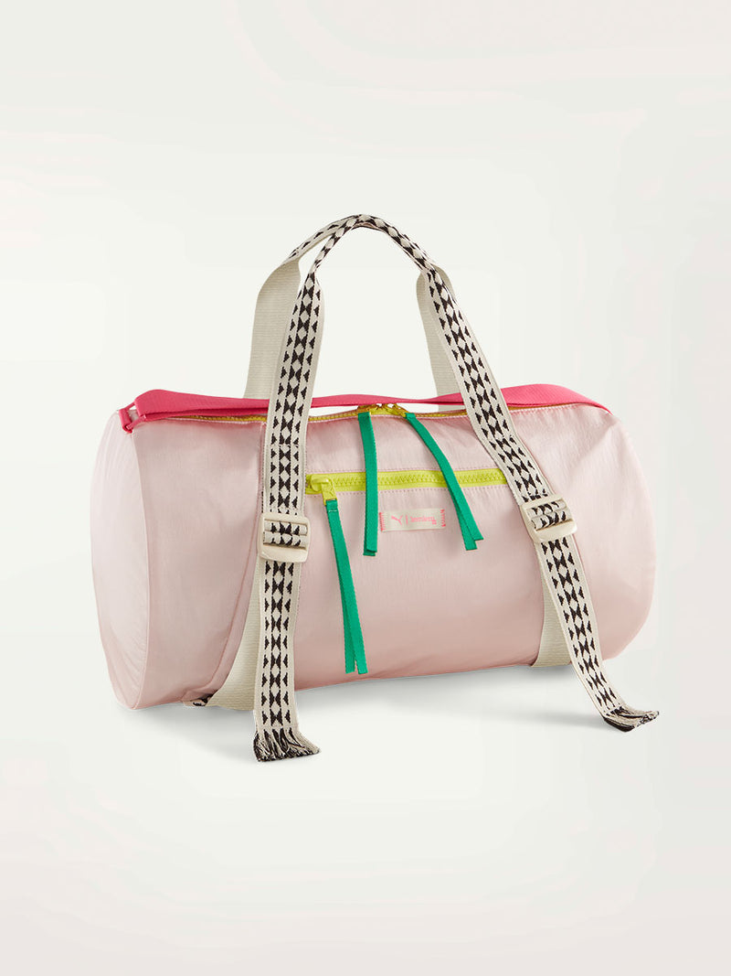 Product Shot of Puma x lemlem studio bag in frosty pink color featuring shoulder straps with classic lemlem triangle print and color block zipper details