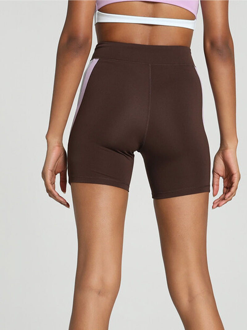 Back View of a Woman Standing Wearing Puma x lemlem Biker Shorts Featuring Dark Chocolate Color and color block details on hips in Violet and White Colors and a matching tank top