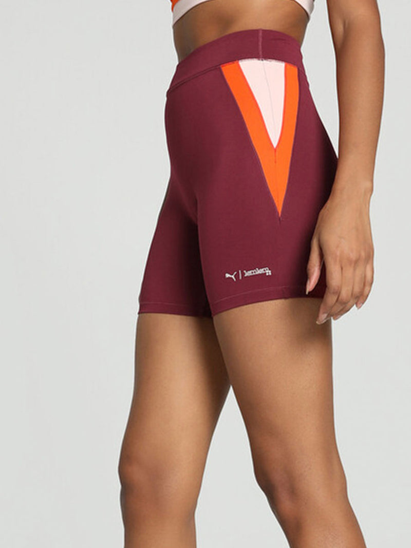 Side View on Legs of a woman standing wearing Puma x lemlem Biker Shorts Featuring Team Regal Red Color and color block details on hips in Warm White and Cayenne Pepper Colors
