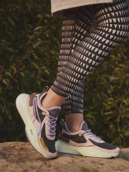 Close up on a Woman's legs Standing Wearing Puma x lemlem PWR Nitro Sneakers featuring rose quartz and dark chocolate colors and high waist leggings