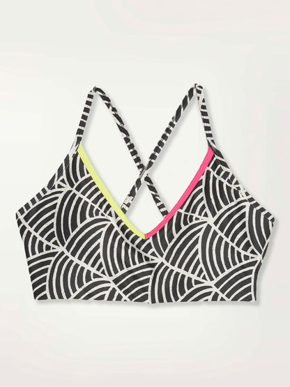  Product Shot of a Puma x lemlem low impact bra featuring hand sketched scallop print in Ghost Pepper  and Black colors and color block side stripes in bright pink and green colors