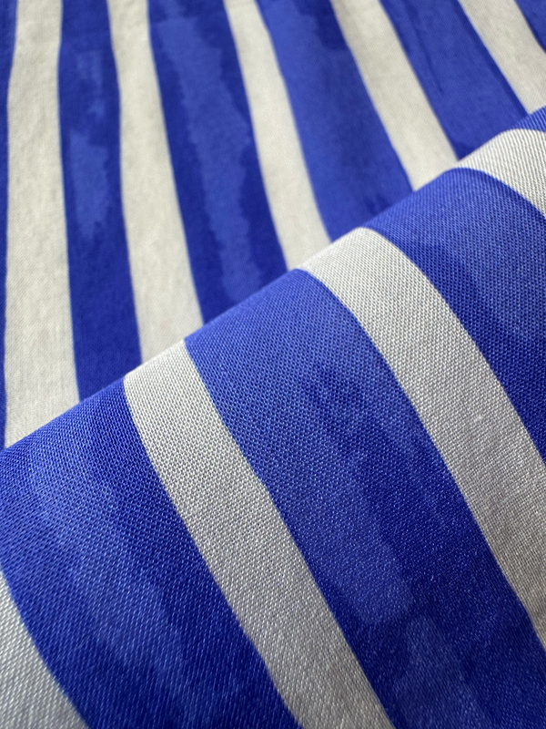 close up on lemlem fabric  featuring an exclusive in-house designed painted-effect stripe print in a vibrant, dazzling blue on a white background