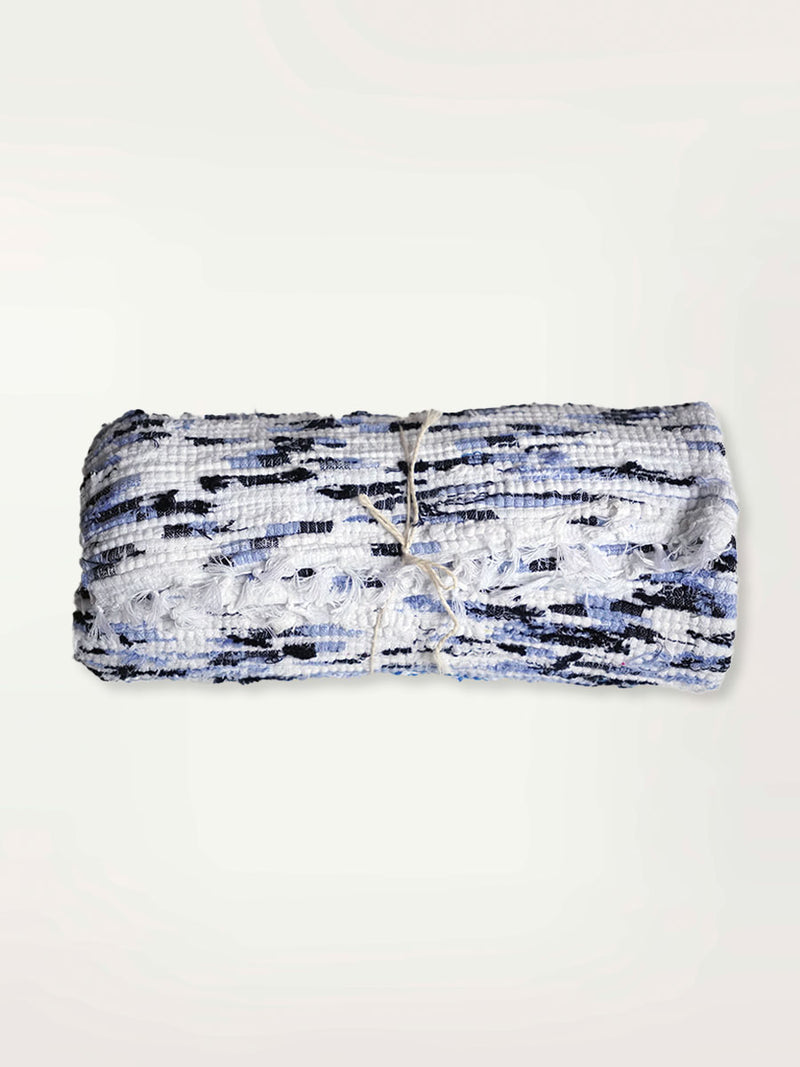 Product Shot of a Rolled Rug Featuring White, Blue and Black Colors