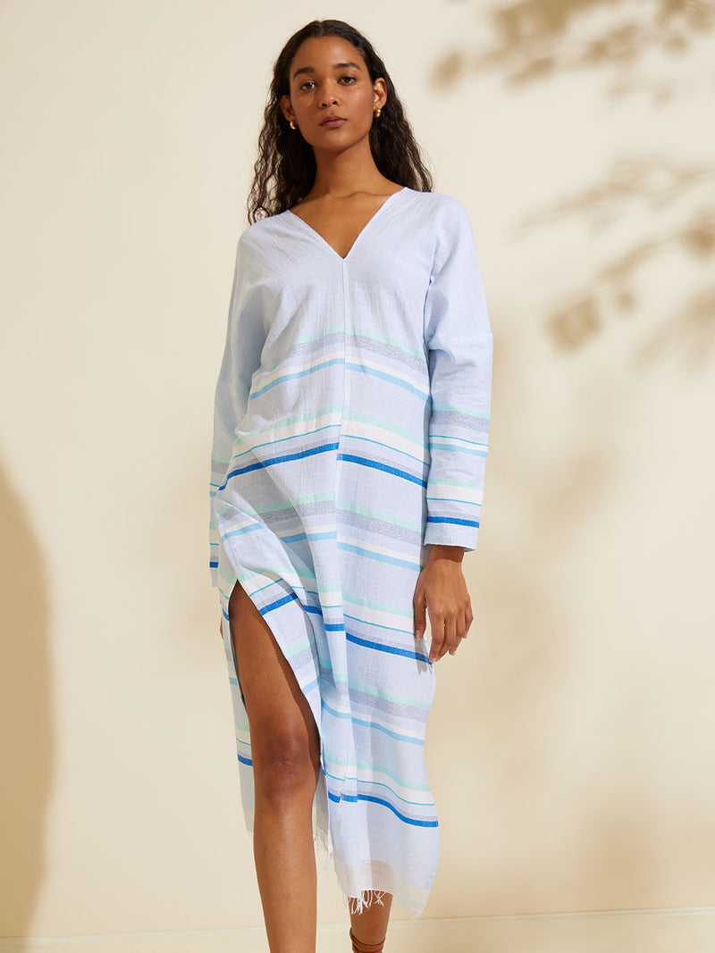 Woman walking wearing the Ruki Long Sleeve Split Caftan featuring a mutli tonal stripe pattern in five shades of blue with silver and white accents.