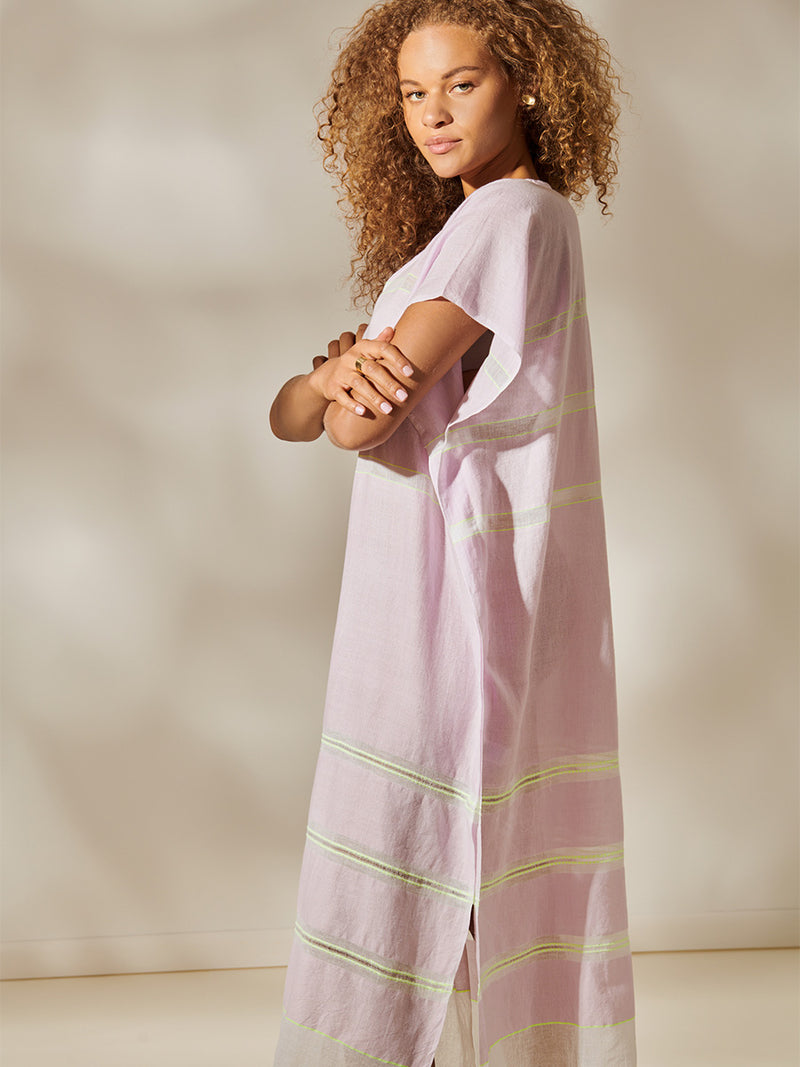 Side view of a Woman Standing Wearing Ruti Dalila V Neck Caftan Featuring lilac orchid color complemented by hints of citron neon.