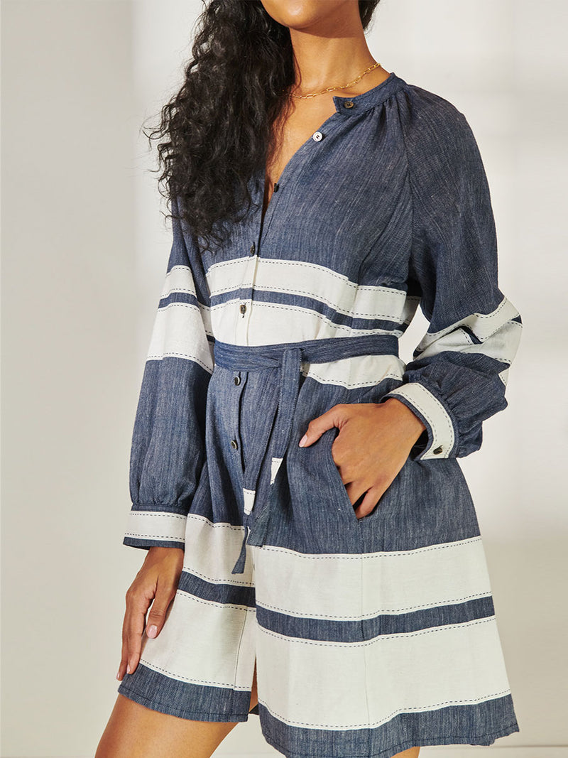 Close up on a Woman Standing Wearing lemlem Meaza Button Up Dress Featuring Bold Stripe Pattern with pick stitch edge in Classic Navy and White colors.