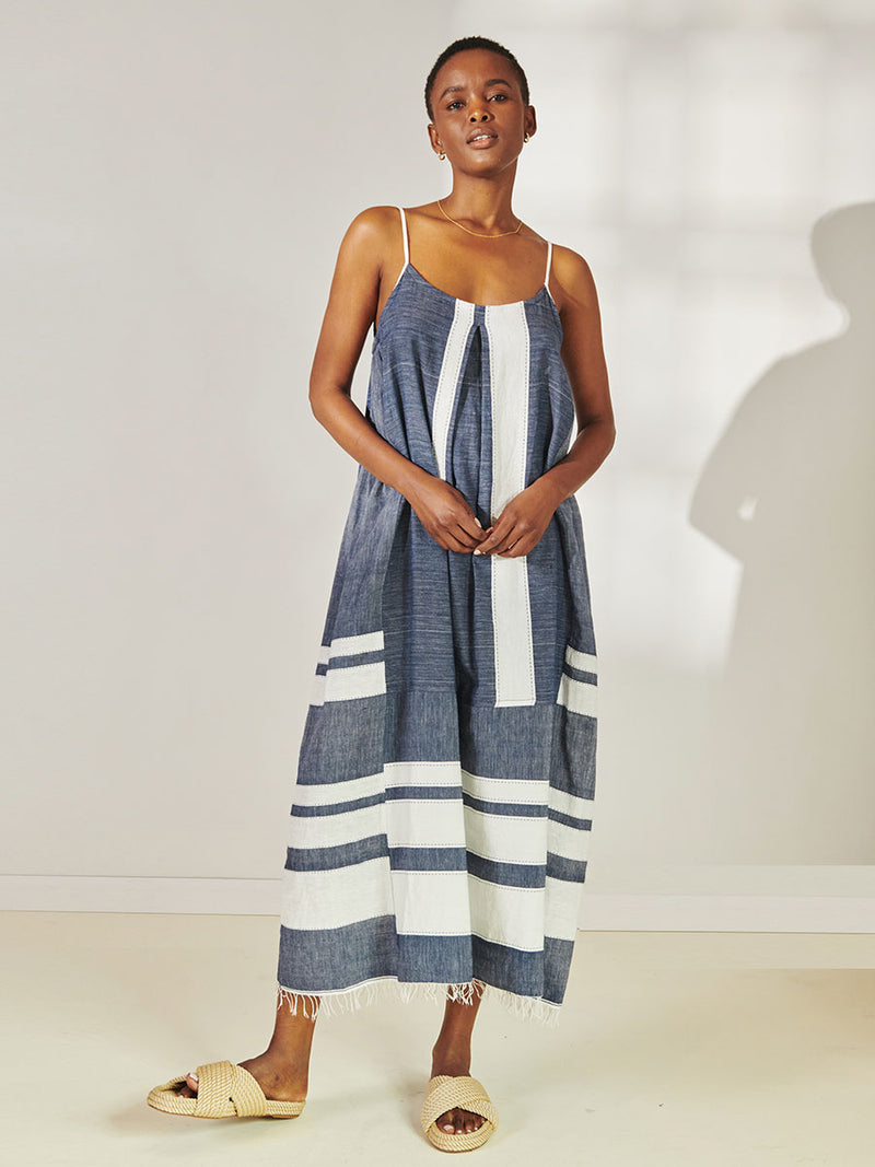 Woman Standing Wearing lemlem Nia Slip Dress Featuring Bold Stripe Pattern with pick stitch edge in Classic Navy and White colors.