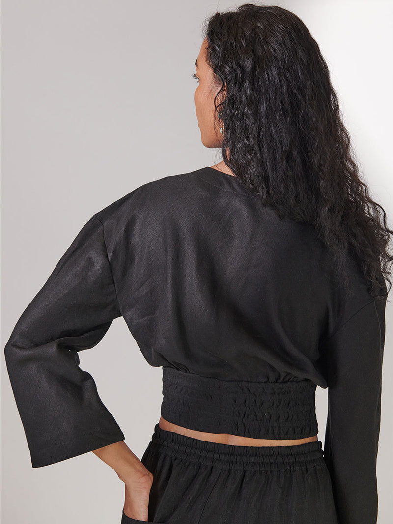 Back View of Woman Standing Wearing lemlem Aurora Plunge Top in Black Color and Matching lemlem Desta Pants