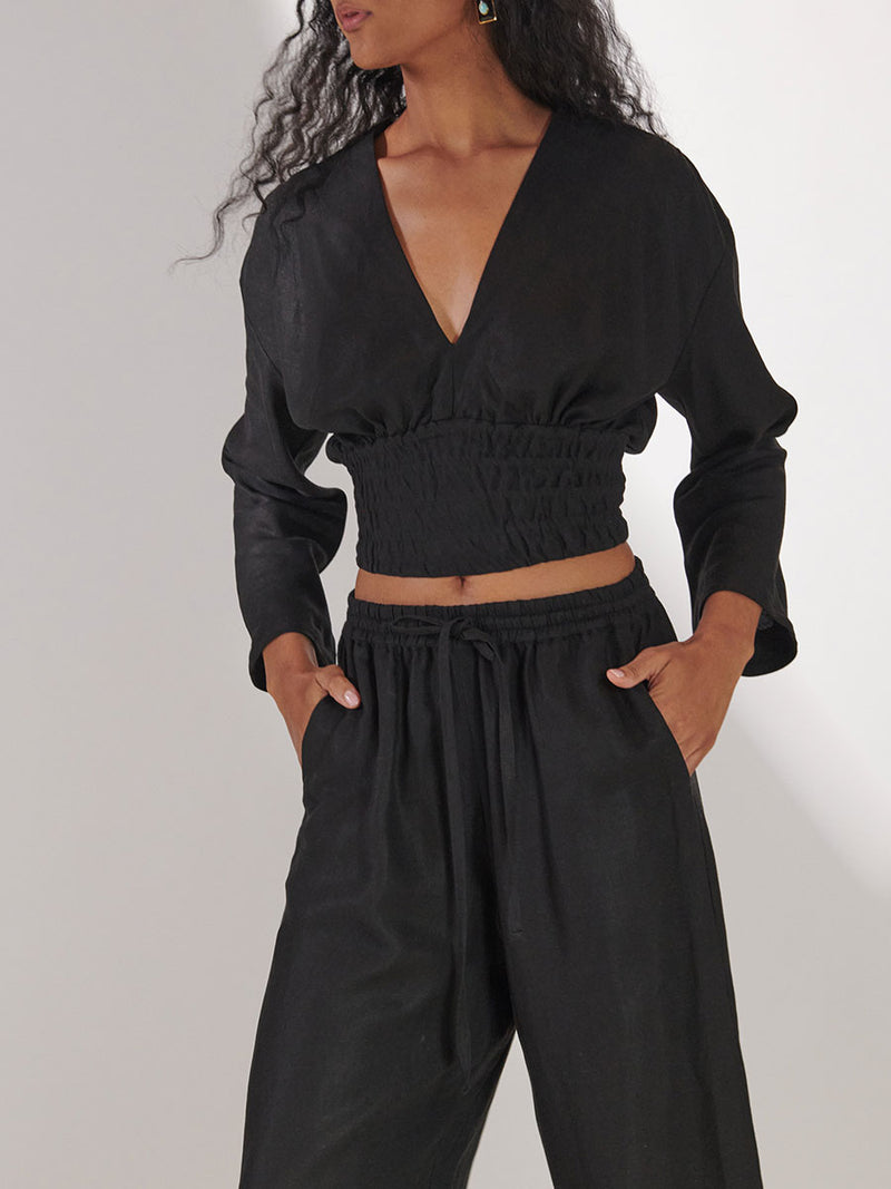 Woman Standing Wearing lemlem Aurora Plunge Top and Desta Pants in black color
